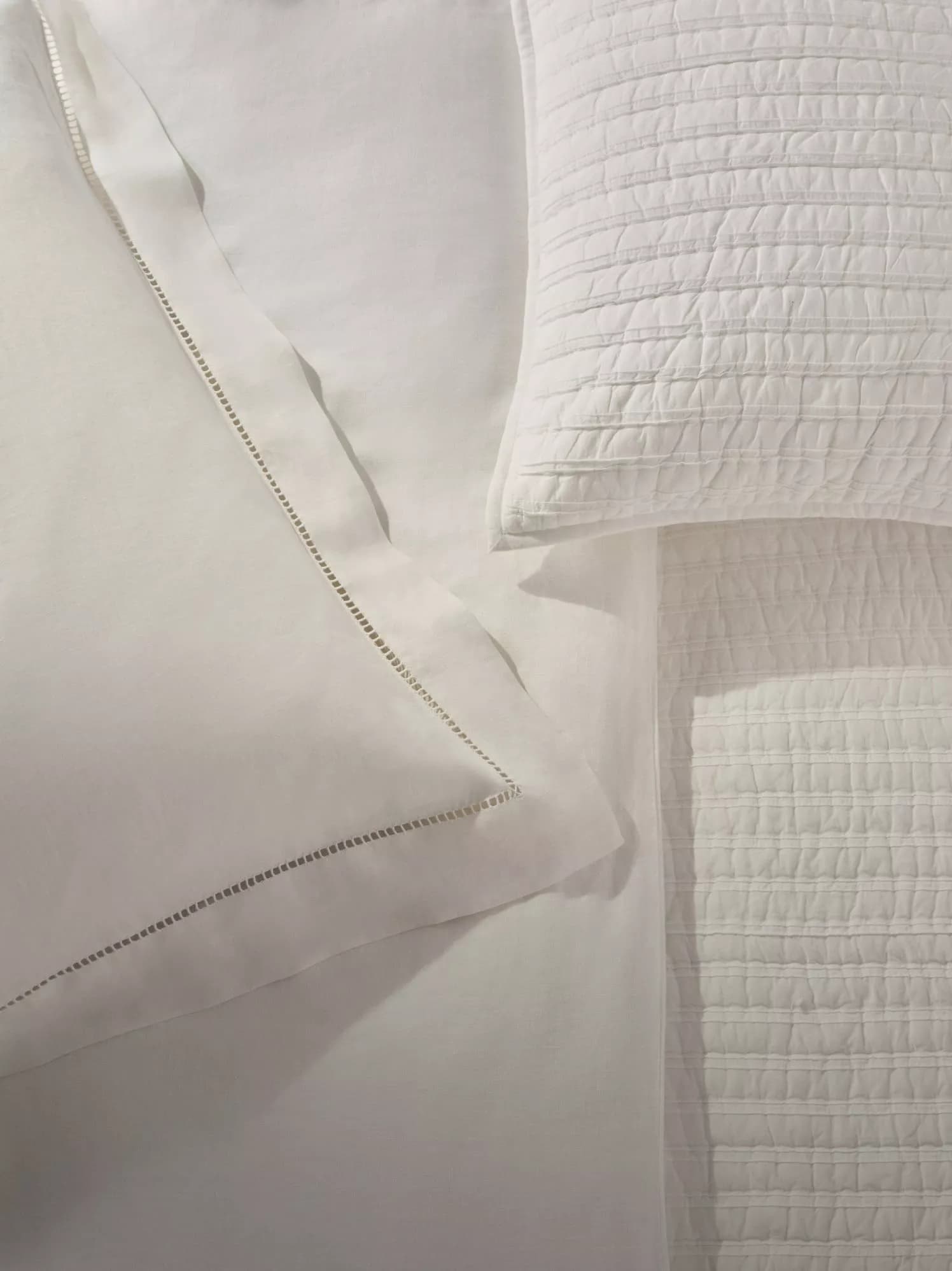 Layered white pillows and quilted bed linen