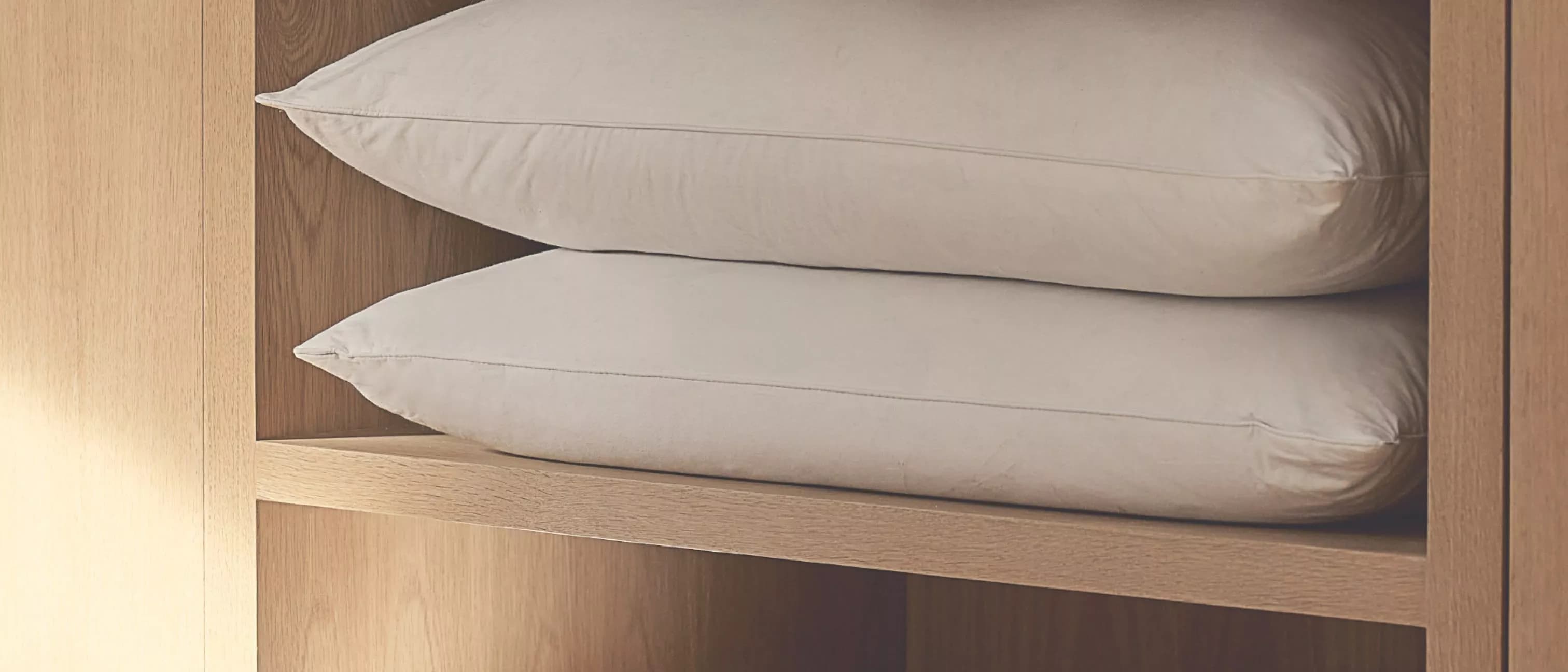 White pillows arranged on a wooden shelf
